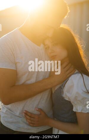 Ritratto verticale di bella giovane coppia romantica in amore abbracciando mentre l'uomo tocca il collo di fidanzate con la mano. Foto Stock