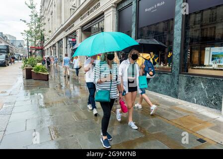 Londra, Regno Unito. 27 luglio 2021. La gente fuori shopping durante una doccia a pioggia in Regent Street. Secondo una nuova analisi condotta da Huq Industries, un’azienda di ricerca sulla mobilità, l’app Covid del Regno Unito ‘pingdemic’ sta causando un significativo rallentamento delle persone che si spostano e visitano i negozi. In tutto il Regno Unito nel mese di luglio, la percentuale media di vendite al dettaglio è scesa del 2.83% e la mobilità del 5.5%. Credit: Stephen Chung / Alamy Live News Foto Stock
