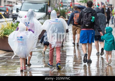 Londra, Regno Unito. 27 luglio 2021. I turisti indossano ponchos fuori shopping durante una doccia a pioggia in Regent Street. Secondo una nuova analisi condotta da Huq Industries, un’azienda di ricerca sulla mobilità, l’app Covid del Regno Unito ‘pingdemic’ sta causando un significativo rallentamento delle persone che si spostano e visitano i negozi. In tutto il Regno Unito nel mese di luglio, la percentuale media di vendite al dettaglio è scesa del 2.83% e la mobilità del 5.5%. Credit: Stephen Chung / Alamy Live News Foto Stock