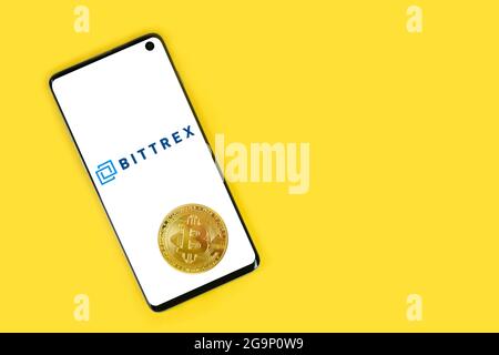 SWANSEA, UK - 4 MAGGIO 2021: Smartphone con logo Bittrex con moneta Bitcoin su sfondo giallo. Servizio di pagamento mobile, investendo in criptovalute Foto Stock