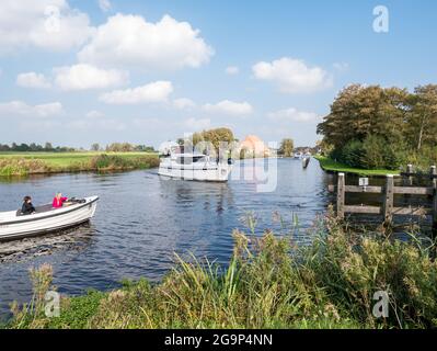 Persone su yacht a motore che navigano sul fiume Boorne ad Akkrum, Friesland, Paesi Bassi Foto Stock