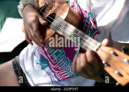 Varsavia, Polonia - 27 giugno 2021: Bambino con lo strumento. Ukulele nelle mani di una ragazza. Un bambino che gioca un piccolo strumento. Foto Stock