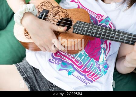 Varsavia, Polonia - 27 giugno 2021: Bambino con lo strumento. Ukulele nelle mani di una ragazza. Un bambino che gioca un piccolo strumento. Foto Stock