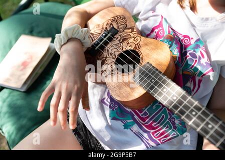 Varsavia, Polonia - 27 giugno 2021: Bambino con lo strumento. Ukulele nelle mani di una ragazza. Un bambino che gioca un piccolo strumento. Foto Stock