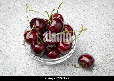 Ciotola in vetro con ciliegie fresche rosse mature e succose Foto Stock