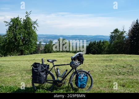 Una bicicletta da turismo molto affollata parcheggiata su un prato con una splendida vista Foto Stock