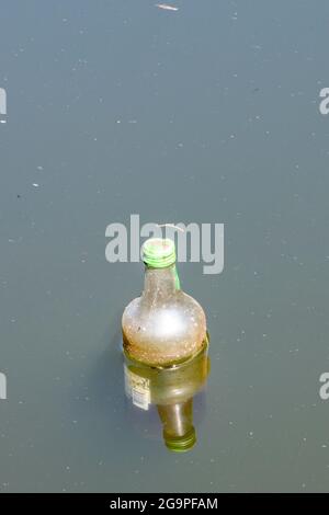 bottiglia vuota che galleggia nel fiume, bottiglia vuota scartata e gettata in un fiume, bottiglia vuota che galleggia in un canale, rifiuti, rifiuti, ambiente. Foto Stock