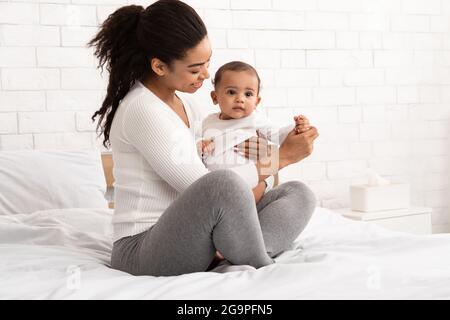 Amorevole madre afroamericana che tiene il suo bambino infantile a casa Foto Stock