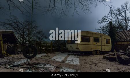 Vecchio rimorchio da campeggio in piedi in una fattoria di notte in inverno, Germania Foto Stock