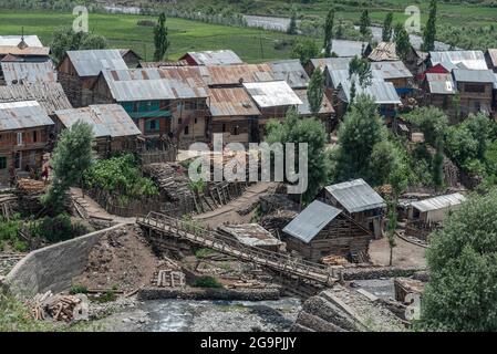 Vista aerea delle case di legno passato Neelam flussi del fiume a Tulail. Gurez si trova lungo la LOC (linea di controllo) nella parte settentrionale del Kashmir. La Valle di Gurez fu la chiave della Via della Seta dall'Europa al Kashgar in Cina e patria della tribù dei Dard di lingua shina, ma non fu aperta al mondo fino al 2007. Prima del 2007, Gurez era aperto solo durante il periodo coloniale, quando i viaggiatori sono venuti per esplorare la valle. La linea di controllo ora attraversa la valle idilliaca, separando i dardi dai loro fratelli Indo-ariani a Gilgit, Chilas e Astore che si trovano in Pakistan. Foto Stock