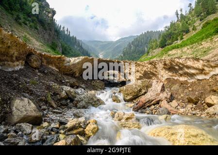 L'acqua scorre quando il ghiacciaio si fonde a Dawar. Gurez si trova lungo la LOC (linea di controllo) nella parte settentrionale del Kashmir. La Valle di Gurez fu la chiave della Via della Seta dall'Europa al Kashgar in Cina e patria della tribù dei Dard di lingua shina, ma non fu aperta al mondo fino al 2007. Prima del 2007, Gurez era aperto solo durante il periodo coloniale, quando i viaggiatori sono venuti per esplorare la valle. La linea di controllo ora attraversa la valle idilliaca, separando i dardi dai loro fratelli Indo-ariani a Gilgit, Chilas e Astore che si trovano in Pakistan. Foto Stock