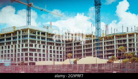 Cantiere con gru a torre sotto un cielo nuvoloso Foto Stock