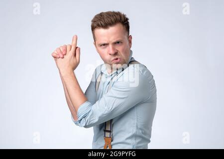 Giovane caucasico gridando con il gesto della mano della pistola. Foto Stock