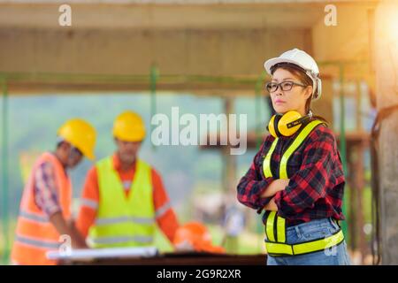 Ispettori e architetti femminili discutono con il capo ingegnere circa progetto di costruzione.Gruppo multietnico di ingegneri che si incontrano nel cantiere in Foto Stock