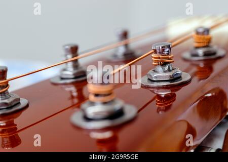 Testa di chitarra con teste di sintonizzazione. Strumenti musicali e concetto di arte musicale. Fuoco selettivo sui pioli con le corde si avvolgono. Primo piano. Foto Stock