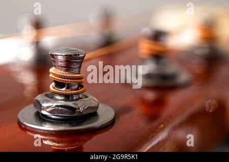 Testa di chitarra con teste di sintonizzazione. Strumenti musicali e concetto di arte musicale. Fuoco selettivo sui pioli con le corde si avvolgono. Primo piano. Foto Stock