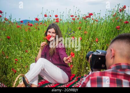 coppia innamorata di uomo e donna che fa foto sulla macchina fotografica in estate campo di fiori papavero, fotografo Foto Stock