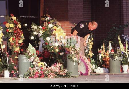 Killeen Texas USA, ottobre 1991: Il poliziotto guarda i fiori lasciati in memoria delle vittime di una sparatoria di massa alla caffetteria di Lusy a Killeen il 16 ottobre. George Hennard, un residente di Killeen di 35 anni, si è schiantato un pick-up nel ristorante e ha sparato 23 pranzo-time cena e il personale a morte prima di uccidersi. ©Bob Daemmrich Foto Stock