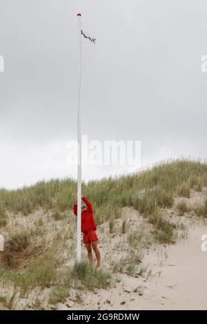 Kampen, Germania. 19 luglio 2021. Il bagnino Jana Kubikova alza la bandiera del tempo di bagno. Credit: Frank Molter/dpa/Alamy Live News Foto Stock