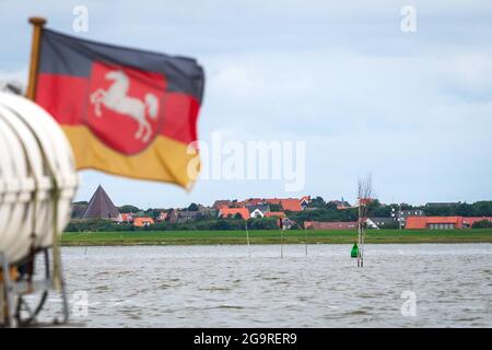 Nordsee, Germania. 22 luglio 2021. Le case di Spiekeroog si possono vedere dietro la bandiera della bassa Sassonia. Credit: Sina Schuldt/dpa/Alamy Live News Foto Stock