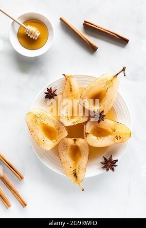 Vista dall'alto delle pere in camicia servite con miele, bastoncini di cannella e anice stellato. Foto Stock