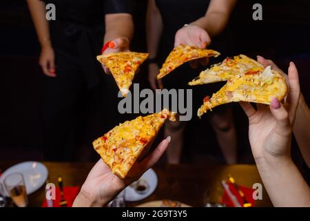 Alta angolazione di un gruppo di persone non riconoscibili le mani ogni afferrando un trancio di pizza Foto Stock