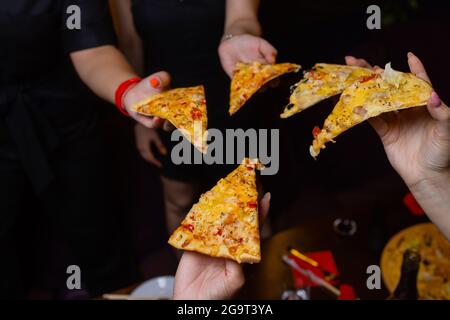 Alta angolazione di un gruppo di persone non riconoscibili le mani ogni afferrando un trancio di pizza Foto Stock