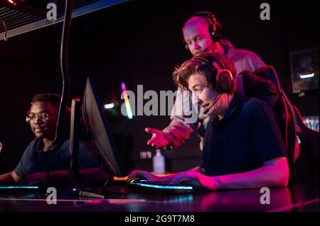 Durante il torneo Dota 2, due ragazzi della squadra giocano al computer, il coach guarda da dietro. Foto Stock