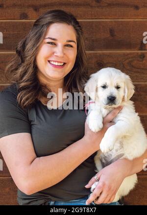 Donna sorridente che tiene siix settimana vecchio platino, o Crema colorato Golden Retriever cucciolo Foto Stock