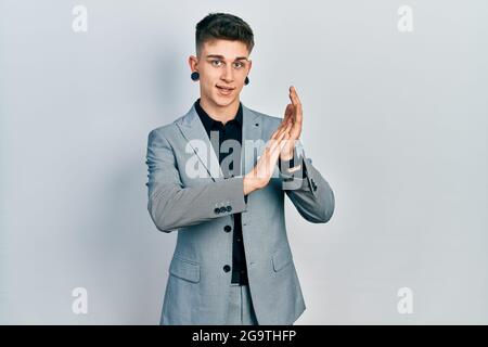 Ragazzo caucasico giovane con le orecchie dilatazione indossare giacca da lavoro aggrappando e applaudendo felice e gioioso, sorridendo mani orgogliose insieme Foto Stock