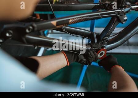 primo piano della mano di un meccanico di bicicletta utilizzando una chiave a staffa inferiore Foto Stock