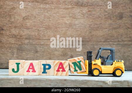 Giocattolo giallo carrello attesa blocco lettera N per completare la parola Giappone su uno sfondo di legno Foto Stock