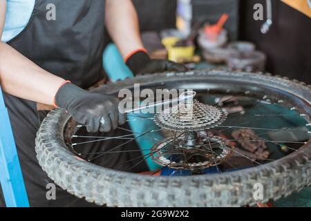 primo piano della mano di un meccanico nei guanti che bloccano un distanziale utilizzando una chiave Foto Stock