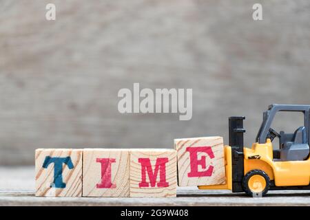 Carrello giocattolo tenere blocco lettera e per completare il tempo parola su sfondo legno Foto Stock