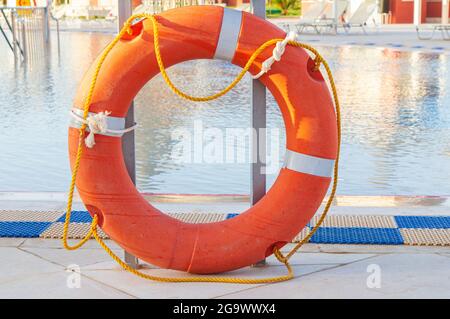 Bagnoschiera arancione con corde su un pavimento piastrellato vicino alla piscina Foto Stock