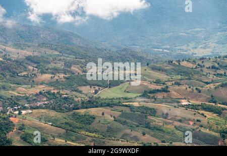 Campo di piantagione del contadino locale sulla collina vicino all'alta montagna del parco nazionale, coperto dalla nebbia leggera nella mattina presto, vie di fronte Foto Stock