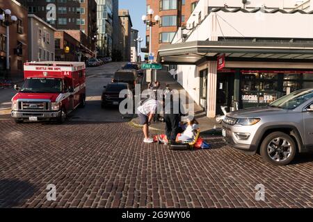 Seattle, Stati Uniti. 27 luglio 2021: Un pilota infortunato e-bike bike-share al mercato pike Place dopo una collisione con un veicolo in ritardo nella giornata. La nuova moto e gli scooter non dovrebbero essere guidati sui marciapiedi, ma le aziende non sono inoltre tenute a fornire caschi per i motociclisti per conformarsi alle leggi locali sui caschi della città. In questo modo i piloti si trovano in un luogo difficile per cavalcare i marciapiedi in pericolo di pedoni o per guidare nel traffico con veicoli in pericolo e quindi infrangendo le leggi sul casco. Credit: James Anderson/Alamy Live News Foto Stock