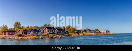 Ohtakari, Finlandia - 25 luglio 2021: Idilliaco paesaggio del Mar Baltico con cottage rossi sulla costa sotto un cielo blu in autunno Foto Stock