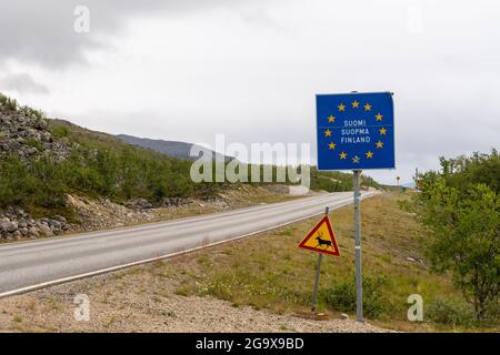 Un cartello di frontiera e un cartello di attraversamento delle renne al confine finlandese nella Lapponia settentrionale Foto Stock