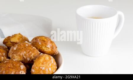 le chouquettes francesi puffs con i perles di zucchero sul piatto con la tazza bianca del caffè. Pasticceria Choux panetterie francesi classiche. Foto Stock