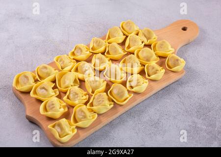 Tortelloni non cotti con farcitura di funghi su tavola di legno. Cucina italiana Foto Stock