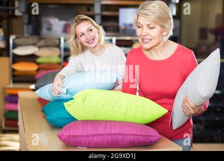 interessati giovani e anziani clienti che guardano attraverso i cuscini nel negozio di tessuti Foto Stock