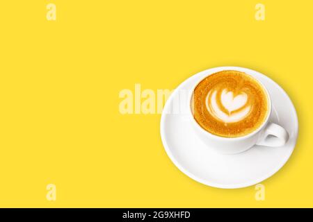 Tazza bianca di cappuccino con latte art su sfondo giallo. Foto Stock
