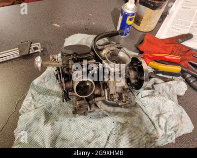 BOURNEMOUTH, REGNO UNITO - 08 luglio 2021: Un carburatore V-Twin su un bBench con WD-40 e gli attrezzi in un negozio di riparazione a Bournemouth, Regno Unito Foto Stock