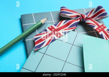 Cancelleria e nastro in colori di bandiera inglese su sfondo blu, closeup. Concetto di apprendimento dell'inglese Foto Stock