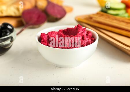 Ciotola con gustoso hummus di barbabietola su sfondo chiaro Foto Stock