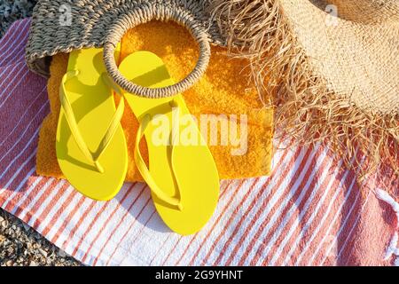 Infradito, asciugamano, borsa e cappello sulla sabbia, guardaroba Foto Stock