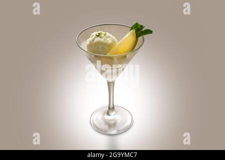 Sorbetto al limone con fetta di limone e foglie di menta in vetro di martini su sfondo marrone chiaro, spazio copia Foto Stock