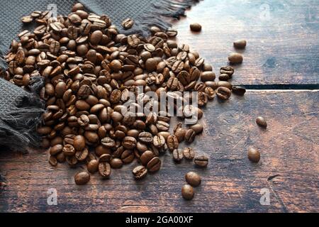 Chicchi di caffè arrosto su legno rustico per una bevanda calda profumata e aromatica con e senza caffeina, spazio di copia, fuoco selezionato, profondità di campo stretta Foto Stock