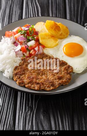 Silpancho è un popolare cibo boliviano che consiste di uno strato di base di riso, patate a fette, carne fritta in pezzi, uova chiodo di garofano nel piatto sul tavolo. Foto Stock
